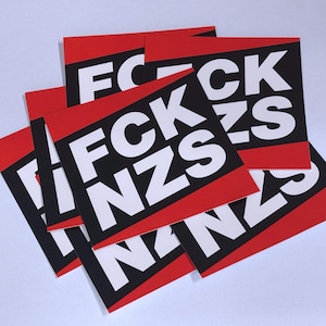 Puede incluir: Un conjunto de pegatinas rojas y negras con el texto "FCK NZS" en letras blancas en negrita. Las pegatinas tienen forma rectangular con una banda roja en la parte superior e inferior.