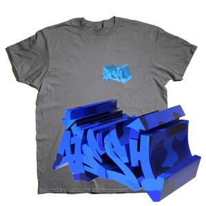Könnte beinhalten: Ein graues T-Shirt mit einer blauen 3D-Grafik des Wortes "ASPHALT" auf der Vorderseite. Die Grafik wird in größerer Größe auf der Unterseite des Shirts wiederholt.