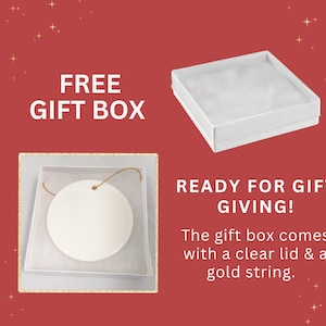 K&ouml;nnte beinhalten: Ein wei&szlig;er Keramik-Anh&auml;nger mit einer goldenen Schnur, bereit zum Verschenken. Er kommt in einer wei&szlig;en Geschenkbox mit einem durchsichtigen Deckel.