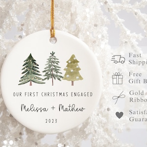 Peut inclure: Ornement de No&euml;l en c&eacute;ramique blanche avec trois sapins verts en aquarelle et le texte "OUR FIRST CHRISTMAS ENGAGED Melissa + Mathew 2023".