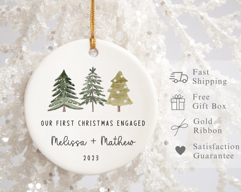 Peut inclure: Ornement de No&euml;l en c&eacute;ramique blanche avec trois sapins verts en aquarelle et le texte "OUR FIRST CHRISTMAS ENGAGED Melissa + Mathew 2023".