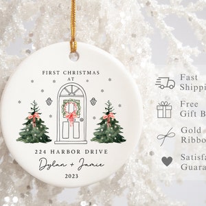 K&ouml;nnte beinhalten: Wei&szlig;er Keramik-Weihnachtsbaumschmuck mit einer handgezeichneten Illustration eines Hauses mit einem Kranz an der T&uuml;r und zwei Weihnachtsb&auml;umen. Der Anh&auml;nger tr&auml;gt die Aufschrift "First Christmas at 224 Harbor Drive Dylan + Jamie 2023".