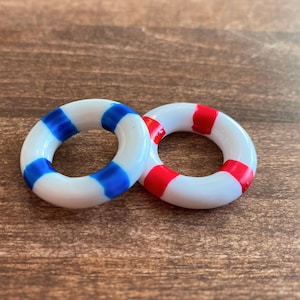 May include: Two white plastic rings with blue and red stripes. The rings are similar to life preservers.