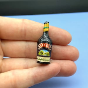以下が含まれることがあります： ベイリーズアイリッシュクリームのミニチュアボトルレプリカ。ボトルは茶色で、金色のラベルと緑と金のキャップが付いています。ラベルには「ベイリーズオリジナルアイリッシュクリームリキュール」と書いてあります。