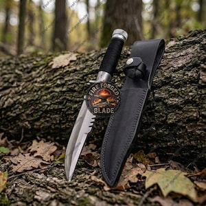 Könnte beinhalten: Ein Messer mit feststehender Klinge aus silberfarbenem Metall, einem mit schwarzer Kordel umwickelten Griff und einem Metallknauf. Das Messer wird von einer schwarzen Lederscheide mit Druckknopfverschluss begleitet. Ein kreisförmiges Logo mit Ambossgrafik ist sichtbar.