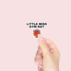 Può includere: Un adesivo con un personaggio dei cartoni animati con un cappello rosa e il testo "Little Miss Gym Rat".