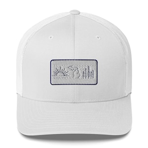 Puede incluir: Gorra de camionero blanca con un parche bordado en azul marino que representa una salida del sol, una silueta del estado de Michigan y una fila de pinos.
