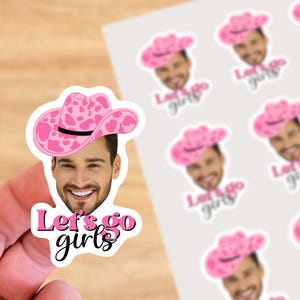 Peut inclure: Autocollant en forme de chapeau de cowboy à imprimé vache rose et blanc avec le visage d'un homme et le texte "Let's go girls".