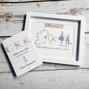 May include: A white framed print featuring the word ENGAGED, a map of Ireland with a heart, a hand-drawn heart with Dublin 25/10/2025, and a silhouette of a proposal. Beside it, a card displays the word GRÁ, Melissa and Karl, 25th October 2025.