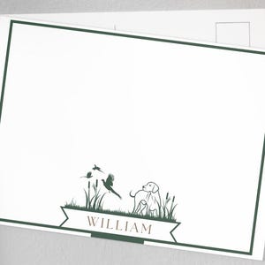 May include: A white card with a green border and a green illustration of a dog and birds in a field. The text "WILLIAM" is printed in brown at the bottom of the card.