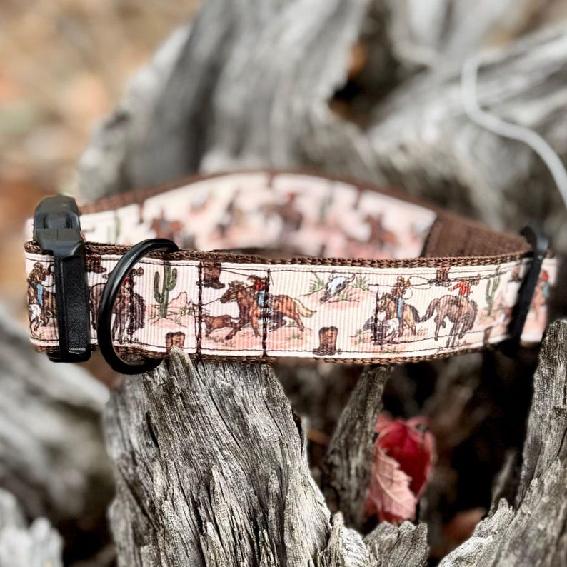 A dog collar with a western theme. The collar features a repeating pattern of cowboys, horses, cacti, and boots on a cream-colored background. The edges are brown, and the hardware is black.