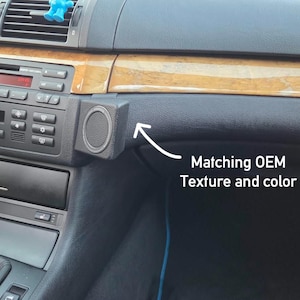 May include: A black textured car dashboard mount with a circular magnetic center, installed next to the radio unit. An arrow points to the mount with the text Matching OEM Texture and color, highlighting the finish of the automotive accessory.