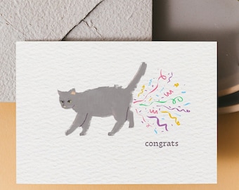 May include: A gray cat with a yellow ear tag is shown on a white card with the word "congrats" printed below. The cat is depicted as having a burst of colorful confetti coming out of its rear end.