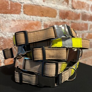 Peut inclure: Un ensemble de quatre colliers pour chien. Les colliers sont en toile brune avec des coutures noires et des boucles argentées. Le collier du haut a une bande réfléchissante jaune et noire.