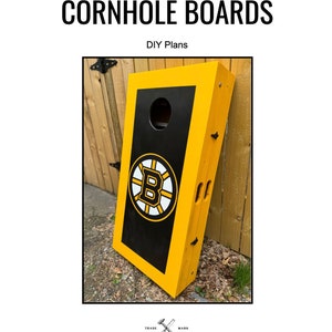 Può includere: Piani fai-da-te per costruire un set di tavole da cornhole. Le tavole sono dipinte di giallo con bordi neri e presentano un logo dei Boston Bruins. Le tavole sono appoggiate a una recinzione di legno.