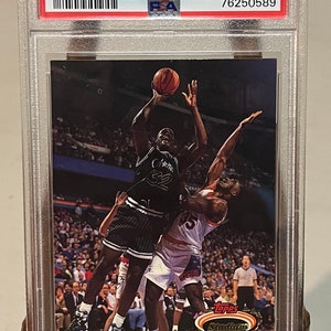 Può includere: Una carta da basket Topps Stadium Club del 1992 con Shaquille O'Neal in una divisa bianca e nera degli Orlando Magic, con il testo "#201 NM-MT 8 76250589" e "MEMBERS CHOICE" sulla carta.
