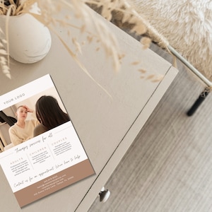 May include: A flyer with the text "YOUR LOGO" at the top, and "Therapy services for all" in the center. The flyer includes information for adults, children, and couples. The flyer is on a neutral-toned surface.