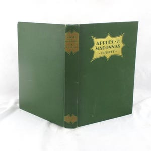 May include: A hardcover book titled "Apples & Madonnas" by Bulliet. The book has a dark green cover with gold lettering and a decorative gold emblem. The spine also features gold lettering and a small emblem.