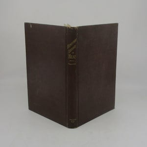 May include: A vintage book titled "Elementary Lessons in Heat" by Tillman. The book has a dark brown cover and spine with gold lettering. The book is open, displaying the spine and the edges of the pages.