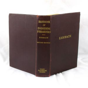 May include: A dark brown hardcover book titled Handbook of Engineering Fundamentals, Second Edition, by Eshbach, part of the Wiley Handbook Series. The front cover and spine feature gold lettering, with the author name Eshbach on the front cover.
