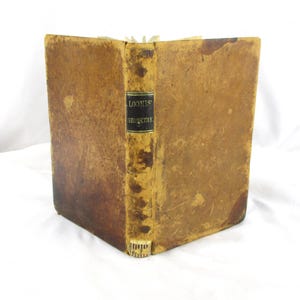 May include: An antique book with a worn, tan leather cover. The spine features the title "LOOMIS' GEOMETRY" on a black label. The book's pages are slightly yellowed, suggesting age. The overall aesthetic is vintage and well-loved.