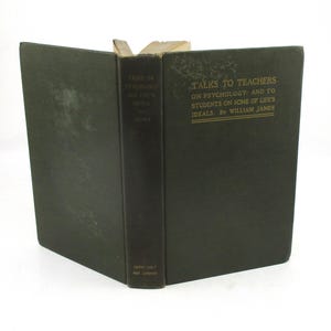 May include: An open, vintage book with a dark green cover and spine. The title "TALKS TO TEACHERS" is printed in gold lettering. The book's pages are aged, and the overall aesthetic suggests a classic, scholarly work.