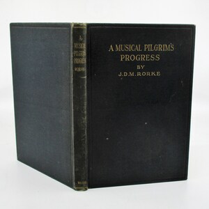 May include: A black hardcover book titled "A Musical Pilgrim's Progress" by J.D.M. Rorke.