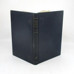 May include: An open book with a dark blue cover and a black spine. The spine features gold lettering that reads "Milk and Dairy Products" and the author's name. The book is slightly open, revealing the pages.