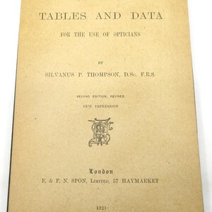 Peut inclure: Un livre intitul&eacute; "Optical Tables and Data" &agrave; l'usage des opticiens, par Silvanus P. Thompson, D.Sc. F.R.S. Deuxi&egrave;me &eacute;dition, r&eacute;vis&eacute;e. Nouvelle impression. Publi&eacute; &agrave; Londres par E. & F. N. Spon, Limited, 57 Haymarket en 1921.