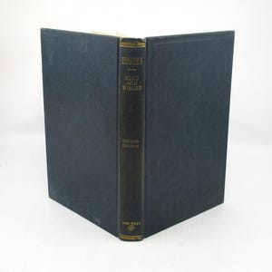May include: An open book with a dark blue cover and spine. The spine reads "Hydraulics" above "King and Wisler" and "Second Edition." The book is from John Wiley & Sons. The pages are yellowed with age.