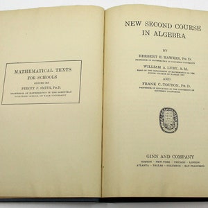 May include: A book titled "New Second Course in Algebra" by Herbert E. Hawkes, Ph.D., William A. Luby, A.M., and Frank C. Touton, Ph.D. The book is part of the "Mathematical Texts for Schools" series edited by Percy F. Smith, Ph.D. The book is published by Ginn and Company.