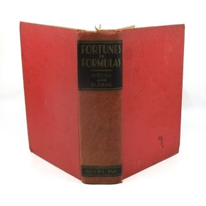 May include: An open book with a red cover and spine. The spine is brown with the title "Fortunes in Formulas" and the authors' names, Hiscox and Sloane, printed in black. The book is from Books, Inc.