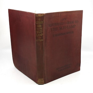 May include: An Illustrated Guide to the Slit-Lamp by T. Harrison Butler. The book has a maroon cover and spine with gold lettering. The title and author's name are visible on the cover and spine. Published by Oxford Medical Publications.