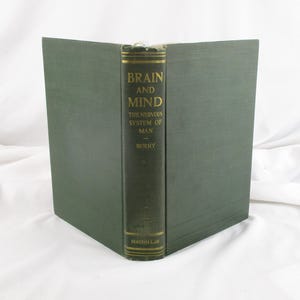 May include: A vintage hardcover book titled "Brain and Mind" with the subtitle "The Nervous System of Man" by Berry. The book has a dark green cover and spine with gold lettering. The publisher's name, Macmillan, is printed at the bottom of the spine.