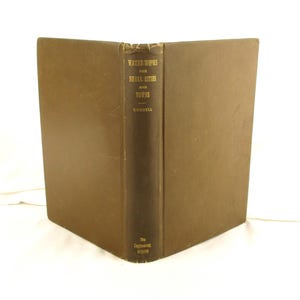 May include: An open, vintage book titled "Water-Works for Small Cities and Towns" by Goodell. The book has a brown cover and spine with gold lettering. The Engineering Record is printed at the bottom of the spine.
