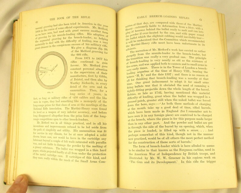 May include: An open book with aged pages, discussing early breech-loading rifles and the Metford grooving for the .303 rifle. The text is in English and includes a diagram and historical details about firearms.