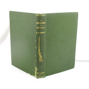 May include: An open, vintage book with a green cover and spine. The spine features gold lettering and a gold illustration of a rifle. The title reads "The Breech-Loader and How to Use It" by W.W. Greener.