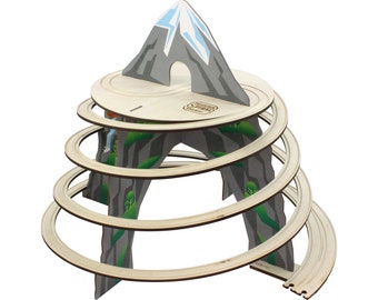 May include: Wooden toy mountain with a spiral track for a toy car. The mountain is gray with a blue snow cap and a tunnel. The track is made of wood and has a green and gray design.