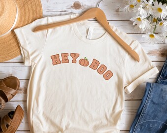 May include: A white t-shirt with the text "Hey Boo" in orange letters with a small orange pumpkin graphic in between the words.