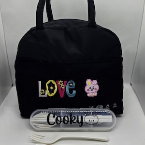 May include: Black insulated lunch bag with embroidered "LOVE" and a cartoon character. Includes a clear case with "Cooky" printed on it, containing a fork, spoon, and chopsticks. A fun and practical lunch set.