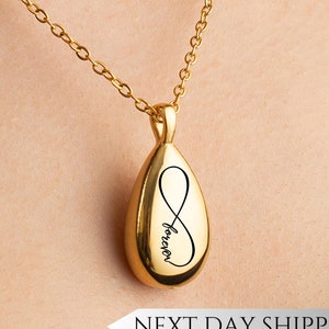 May include: Gold teardrop-shaped pendant necklace with an infinity symbol and the word "forever" engraved on it.