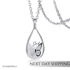 Op de afbeelding: Een zilverkleurige druppelvormige hangerketting. De hanger heeft een vlinder- en bloemdesign met het woord "Dad". De ketting heeft een fijne ketting. De tekst "NEXT DAY SHIPPING" staat onderaan.