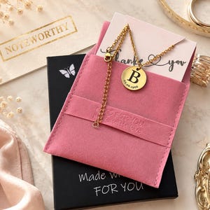 Op de afbeelding: Een goudkleurige ketting met een ronde hanger met de letter "B" en de datum "02.06.1966". De ketting wordt gepresenteerd in een roze etui met de woorden "Made with love FOR YOU". Een kaart zegt "Bedankt".