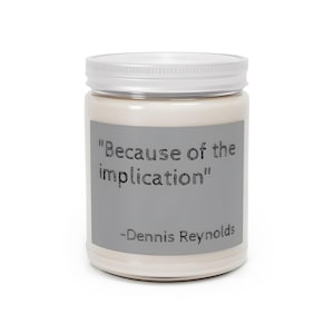 May include: A white jar with a silver lid. The jar has a gray label with the quote "Because of the implication" and the name "-Dennis Reynolds" in black text. The jar is filled with a cream-colored substance.
