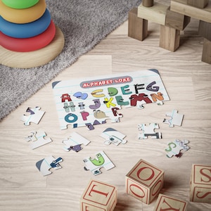 May include: A colorful alphabet puzzle with a white background and the words "Alphabet Lore" printed on the top. The puzzle pieces are scattered on a wooden floor with some wooden blocks that spell out "TOYS".