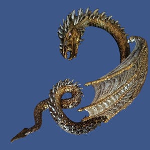 Può includere: Scultura dettagliata di un drago con finiture oro e argento. Il drago presenta una testa dettagliata con bocca aperta, un corpo curvo e ali spiegate. Le squame e i dettagli della scultura sono finemente progettati.