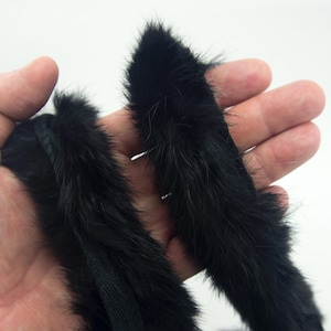 Puede incluir: Borde de piel negra con una textura suave y esponjosa. La piel está dispuesta en una tira larga y estrecha, ideal para añadir un toque de lujo a la ropa o las manualidades.