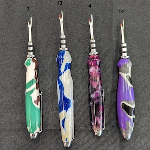 May include: Four different colored thread snips with silver metal tips. The snips are green, blue, purple, and black with white accents. The snips are labeled with numbers 3, 13, 4, and 14.