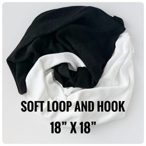 May include: A folded black and white fabric, possibly a towel or cloth, is displayed against a white background. The text "SOFT LOOP AND HOOK" and "18" X 18"" is printed in black on the bottom of the image. The dimensions are 18 inches by 18 inches.