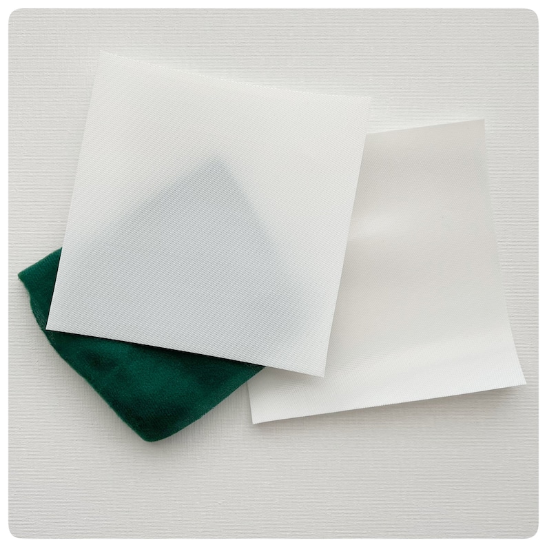May include: Two white sheets of paper, one on top of the other, with a green fabric underneath. The top sheet of paper is slightly larger than the bottom sheet.
